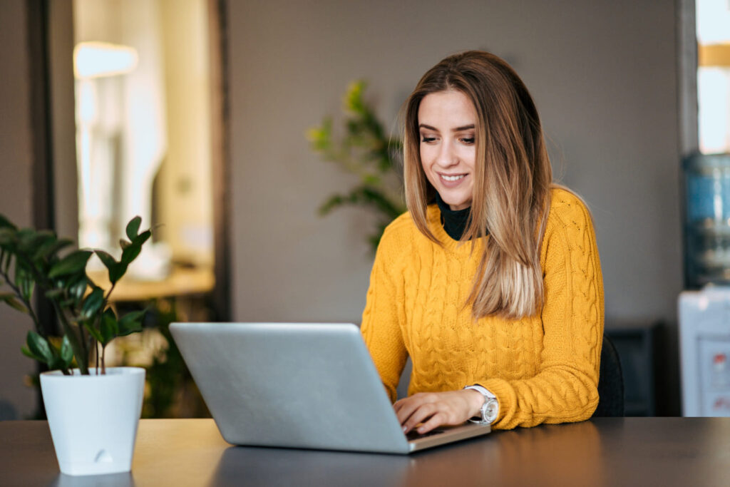 Mulher feliz usando seu laptop e aproveitando os benefícios de Comprar Seguidores Instagram Teste Grátis