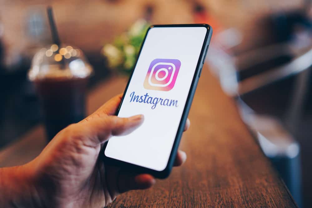 Pessoa segurando um celular com o aplicativo do Instagram aberto, ilustrando ações como apagar comentários diretamente pelo smartphone.