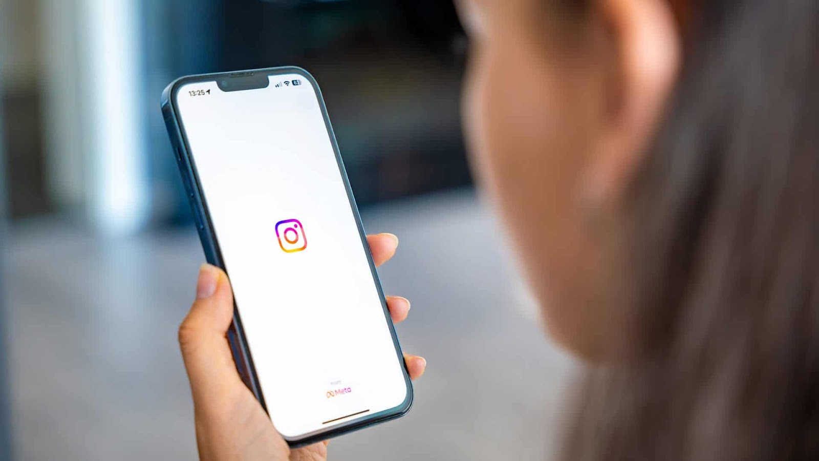 Mulher segurando um smartphone com a tela inicial do Instagram aberta, pronta para acessar suas postagens e apagar comentários indesejados na plataforma.
