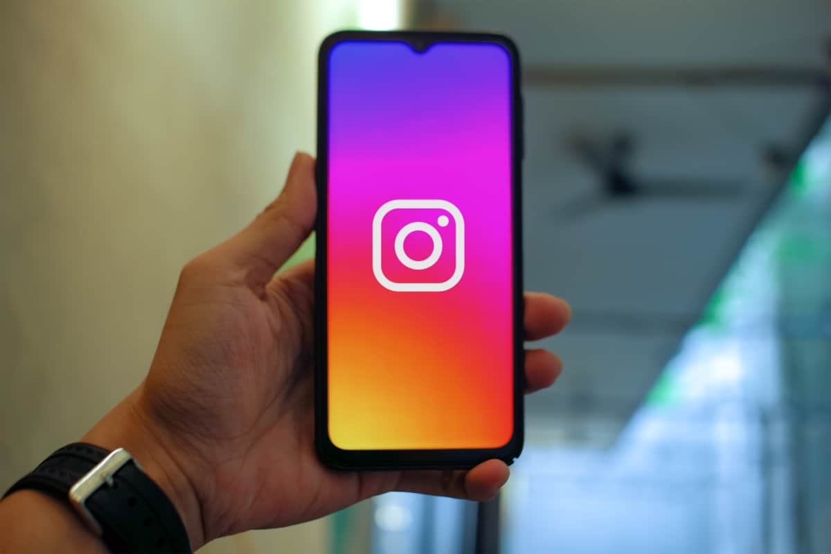 Se começasse a criar conteúdo hoje no Instagram, eu faria isso: Estratégias para construir um perfil de sucesso desde o início 3 Mão segurando um smartphone com o ícone do Instagram em destaque. A imagem representa o acesso e a prontidão para criar conteúdo hoje no Instagram, explorando as possibilidades da plataforma.