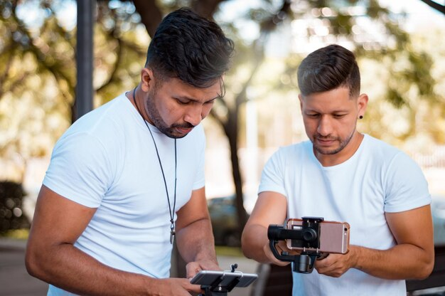 Dois criadores de conteúdo ao ar livre gravando e ajustando equipamentos para produzir Reels no Instagram, mostrando a preparação para criar vídeos de alta qualidade.