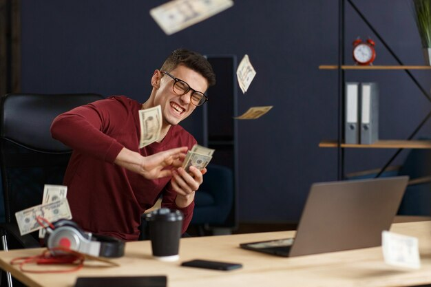 Homem sentado em uma mesa de trabalho, segurando maços de dinheiro enquanto expressa entusiasmo, simbolizando os ganhos financeiros possíveis com o Instagram. Saiba com quantos seguidores começa a ganhar dinheiro no Instagram.