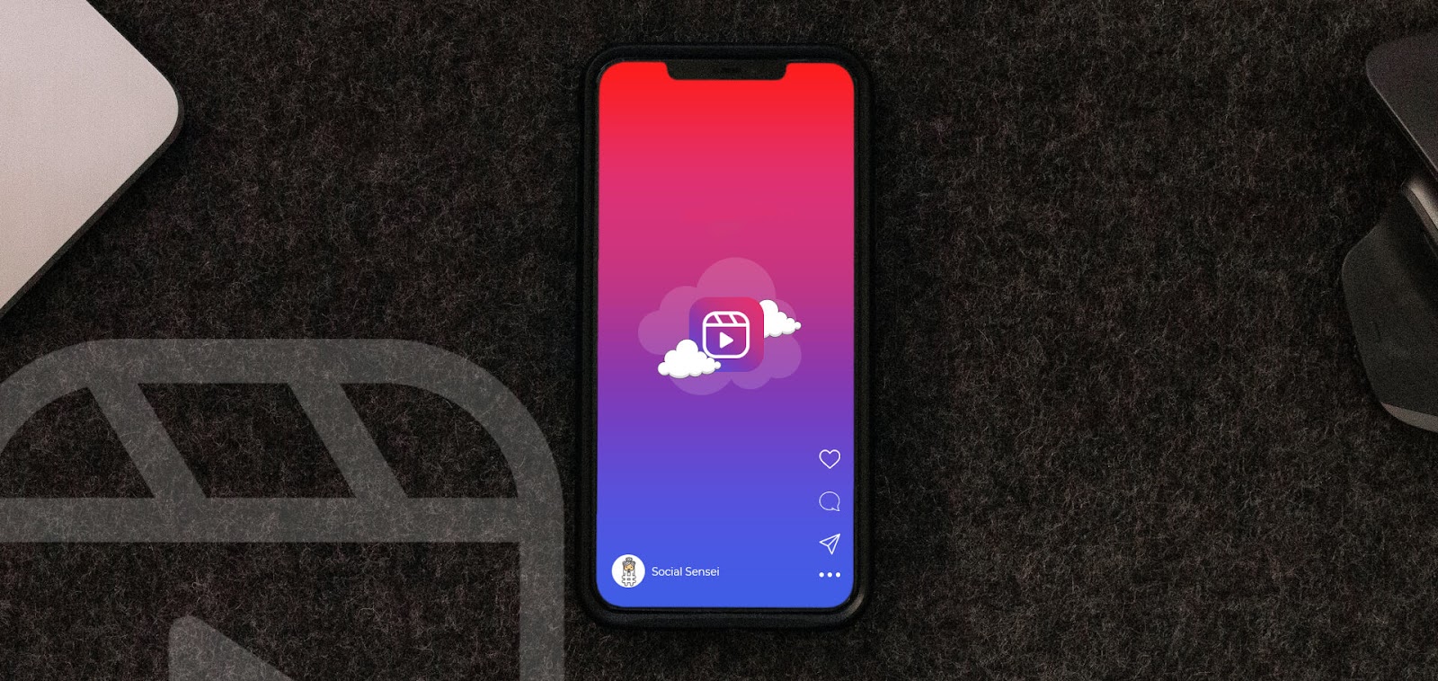 Reels para Empresas: Descubra Como Transformar Vídeos Curtos em Resultados Reais 3 Um smartphone está posicionado sobre uma superfície escura e texturizada. Na tela, um fundo com gradiente de vermelho e roxo exibe um ícone de nuvem com o logo do Reels no centro. Partes de um laptop e um mouse aparecem nas laterais, representando o processo de criação de Reels para empresas.